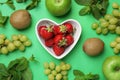 Fresh ripe strawberries, apples, grape, kiwis and mint on green, flat lay