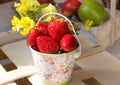 Fresh ripe strawberries in bucket on wood box in garden outdoors, fruits in basket in background Royalty Free Stock Photo