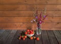 Fresh ripe strawberry and bouquet made of red astilbe and blue bell flowers on wooden table. View with copy space