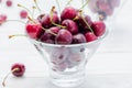 Fresh ripe sweet cherries in water drops in glass bowl on a white wooden table Royalty Free Stock Photo