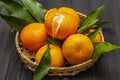 Fresh ripe tangerines with leaves in basket. New Year or Christmas wooden background. Festive good mood concept Royalty Free Stock Photo