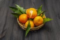 Fresh ripe tangerines with leaves in basket. New Year or Christmas wooden background. Festive good mood concept Royalty Free Stock Photo