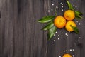 Fresh ripe tangerines with leaves and sprinkles. New Year or Christmas wooden background. Festive good mood concept Royalty Free Stock Photo