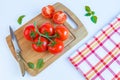 Fresh and ripe tomatoes, basil and knife on cutting board Royalty Free Stock Photo