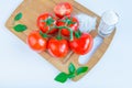 Fresh and ripe tomatoes, basil, salt on cutting board Royalty Free Stock Photo