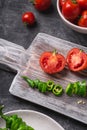 Fresh ripe tomatoes in bowl near to old wooden cutting board with hot chili peppers in plate Royalty Free Stock Photo