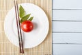 Fresh ripe tomatoes and food sticks on wooden table. White plate on bamboo mat. Top view with copy space Royalty Free Stock Photo