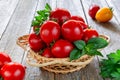 Fresh ripe tomatoes in a wicker plate on a wooden table Royalty Free Stock Photo