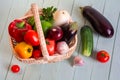 Fresh ripe vegetables in a wicker basket on a white wooden table Royalty Free Stock Photo