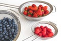 Fresh ripe washed strawberries, blueberries, raspberries in colanders Royalty Free Stock Photo