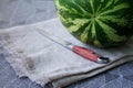 Fresh watermelon on linen tablecloth next to knife, preparing for picnic, selective focus