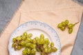 Fresh ripe white grape berries in plate on linen tablecloth, stone concrete background