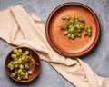 Fresh ripe white grape berries in wooden plate and bowl on linen tablecloth, stone concrete background