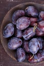 Fresh ripe whole purple damson plums on wooden plate