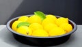 Fresh ripe yellow lemon citrus fruits with green leaves on a dark plate on a gray background.Whole lemons. Royalty Free Stock Photo