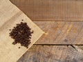 Fresh roasted coffee beans on a burlap bag with a wooden background.