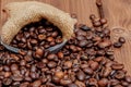 Fresh roasted coffee beans falling out the sack on the wooden surface. Brown coffee beans scattered from bag on the table Royalty Free Stock Photo