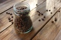 Fresh roasted coffee beans in glass jar on wooden table from above. Scattered coffee beans on wood background Royalty Free Stock Photo