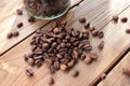 Fresh roasted coffee beans in glass jar on wooden table from above. Scattered coffee beans on wood background Royalty Free Stock Photo