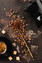 Fresh Roasted whole grains of Arabica coffee scattered, vintage spoon with ground coffee cane sugar, a cup and black coffee on an