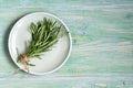 Fresh rosemary bunch on a plate on green wooden background, top view