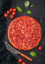 Fresh round baked Hot and Spicy Pepperoni pizza with knife and tomatoes with basil on black background with kitchen cloth. Close Royalty Free Stock Photo