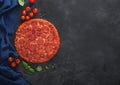 Fresh round baked Hot and Spicy Pepperoni pizza with tomatoes with basil on black background with kitchen blue cloth. Space for