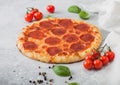 Fresh round baked Pepperoni italian pizza with tomatoes with basil on ligh background with linen towel Royalty Free Stock Photo