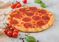 Fresh round baked Pepperoni italian pizza with tomatoes with basil on ligh background with linen towel Royalty Free Stock Photo