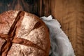 Fresh round home-made rye bread wrapped in cotton gauze lies on the wooden table