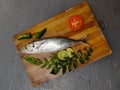 Fresh Round Scad Fish decorated with herbs and vegetables on a wooden pad .Selective Focus