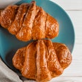 Fresh ruddy croissants with berries lie on a wooden table next to fresh black currant berries, red currants