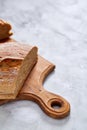 Fresh rye bread loaf on a wooden chopping board over white textured background, shallow depth of field Royalty Free Stock Photo