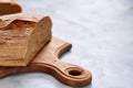 Fresh rye bread loaf on a wooden chopping board over white textured background, shallow depth of field Royalty Free Stock Photo