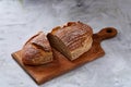 Fresh rye bread loaf on a wooden chopping board over white textured background, shallow depth of field Royalty Free Stock Photo