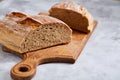 Fresh rye bread loaf on a wooden chopping board over white textured background, shallow depth of field Royalty Free Stock Photo