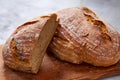 Fresh rye bread loaf on a wooden chopping board over white textured background, shallow depth of field Royalty Free Stock Photo