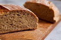 Fresh rye bread loaf on a wooden chopping board over white textured background, shallow depth of field Royalty Free Stock Photo