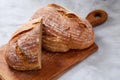 Fresh rye bread loaf on a wooden chopping board over white textured background, shallow depth of field Royalty Free Stock Photo