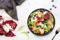 Fresh salad with arugula, radicchio; peaches, smoked pork ham, feta cheese and blueberries. White table background, top view Royalty Free Stock Photo