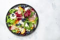 Fresh salad with arugula, radicchio, peaches, smoked pork ham, feta cheese and blueberries. White table background, top view Royalty Free Stock Photo