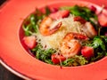 Fresh salad of arugula, shrimp and strawberry. Dark wooden background. Restaurant menu