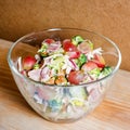 Fresh salad with bacon, grapes, walnuts, greens and herbs and olive oil in transparent glass salad-bowl. Portion of salad on the b