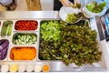 Fresh Salad bar counter with person`s hands lifting Lettuce into a plate for healthy and diet meal with smooth light and shadow Royalty Free Stock Photo