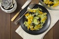 Fresh salad of black olives, iceberg cabbage, yellow bell pepper and cucumber, healthy food flat lay, natural light, wooden table