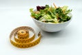 Fresh salad in a bowl and measuring tape. Diet and healthy eating concept Royalty Free Stock Photo