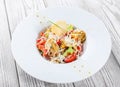 Fresh salad with chicken breast, artichokes, cherry tomatoes, lettuce and cheese parmesan on wooden background close up