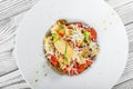 Fresh salad with chicken breast, artichokes, cherry tomatoes, lettuce and cheese parmesan on wooden background close up