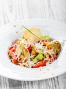 Fresh salad with chicken breast, artichokes, cherry tomatoes, lettuce and cheese parmesan on wooden background