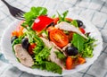 Fresh salad with chicken breast, arugula, black olives,red pepper, lettuce, fresh sald leaves and tomato on a white plate on woode Royalty Free Stock Photo